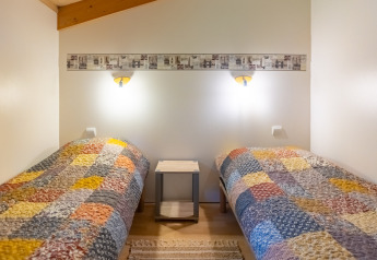 Due letti singoli con trapunte patchwork colorate in uno chalet al Camping Des Randonneurs, Francia.