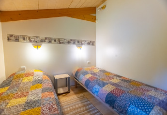Camera accogliente nello Chalet al Camping Des Randonneurs, Francia, con due letti singoli e coperte colorate.