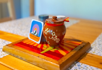 Tavolo colorato con vaso in ceramica, porta spezie e cartolina di montagna al chalet di Camping Des Randonneurs, Francia.