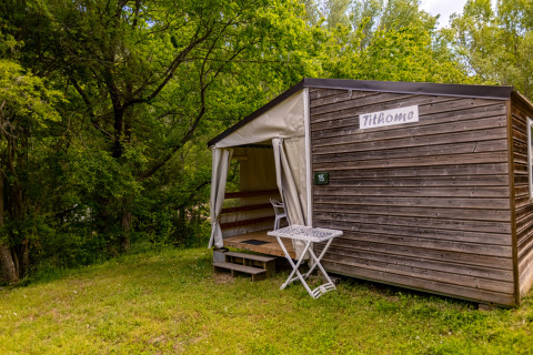 Safaritent Stacaravan Tithome bij Camping Des Randonneurs in Frankrijk, omgeven door groen bos.
