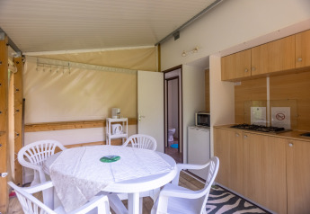Interno della tenda safari Stacaravan Tithome al Camping Des Randonneurs in Francia con cucina e tavolo.