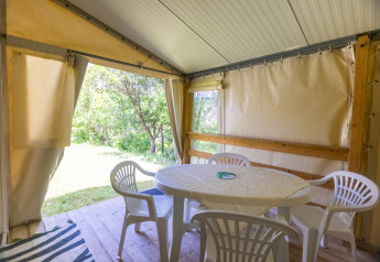 Vue intérieure d'une tente safari avec une table ronde et quatre chaises blanches au Camping Des Randonneurs en France.