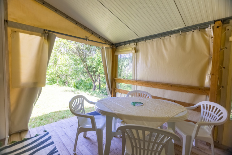 Innenansicht eines Safari-Zeltes mit rundem Tisch und vier weißen Stühlen auf Camping Des Randonneurs in Frankreich.
