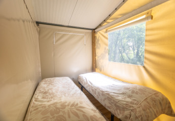 Interior view of a safari tent room with two single beds at Camping Des Randonneurs in France.