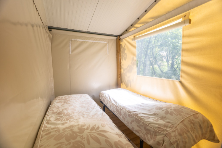 Vue intérieure d'une tente safari avec deux lits simples au Camping Des Randonneurs en France.