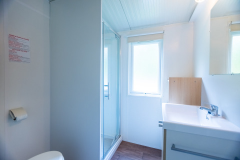 Lichte, moderne badkamer in Stacaravan Tithome op Camping Des Randonneurs in Frankrijk met douche en raam.