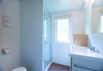 Bright, modern bathroom in Stacaravan Tithome at Camping Des Randonneurs, France, featuring shower and window.