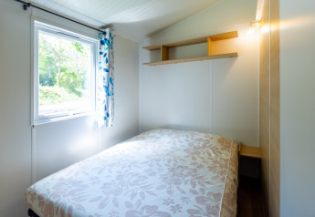 Camera luminosa in Stacaravan Tithome al Camping Des Randonneurs, Francia, con finestra e letto matrimoniale.