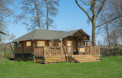 Safaritent Medley Lodge met terras en hottub bij Recreatiepark Den Blanken in Nederland, omgeven door groen.
