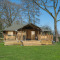 Safari tent Medley Lodge met een veranda, bubbelbad en omringd door gras en hoge bomen in een groene omgeving.