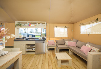 Interior of a safari tent with kitchen, sofa, and wooden furniture in Medley Lodge, Den Blanken, Netherlands.