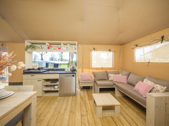 Interior de tienda safari con cocina, sofá y muebles de madera en Medley Lodge, Den Blanken, Países Bajos.