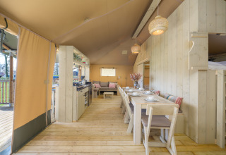 Interior de la tienda safari Medley Lodge con mesa de comedor y cocina en Recreation Park Den Blanken, Países Bajos.