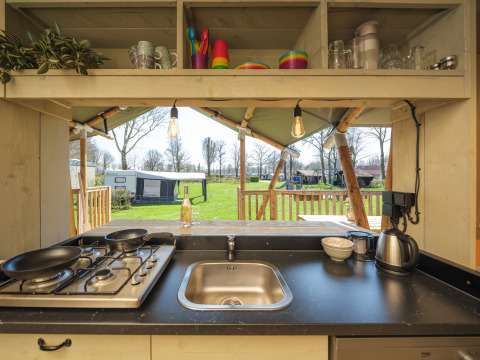 Keuken van een safaritent Medley Lodge met hot tub op Recreatiepark Den Blanken in Nederland, buitenzicht.