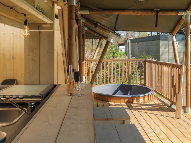 Terraza de madera con asientos y jacuzzi en la tienda safari Medley Lodge, Recreation Park Den Blanken.