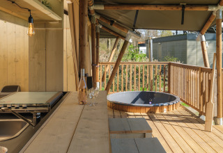 Terraza de madera con asientos y jacuzzi en la tienda safari Medley Lodge, Recreation Park Den Blanken.