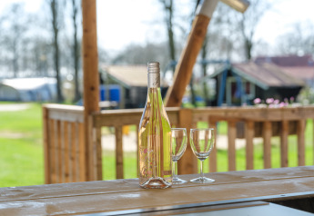 Bouteille de vin et deux verres sur table en bois dans une tente safari à Medley Lodge, Den Blanken, Pays-Bas.