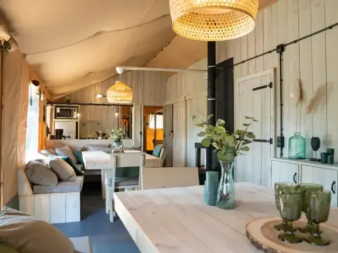 Indvendigt billede af Medley Lodge safaritelt med boblebad, lyst træinteriør og charmerende dekoration.