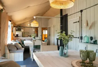Vista interna della tenda safari Medley Lodge con vasca idromassaggio, arredo in legno chiaro e atmosfera accogliente.