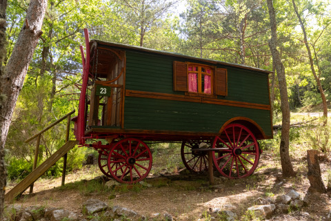 Carro gitano pintoresco con ruedas rojas y escaleras, en el bosque del Camping Des Randonneurs, Francia.