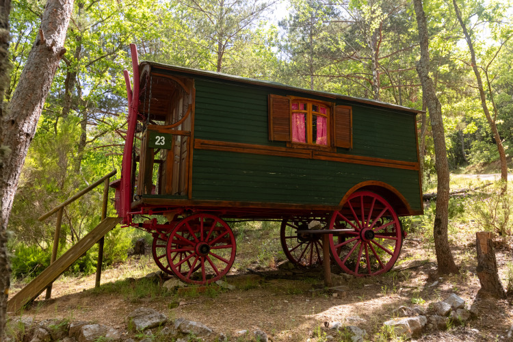 Carro gitano pintoresco con ruedas rojas y escaleras, en el bosque del Camping Des Randonneurs, Francia.