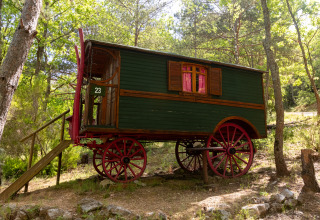 Carro gitano pintoresco con ruedas rojas y escaleras, en el bosque del Camping Des Randonneurs, Francia.