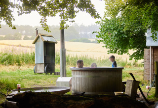 Gezin geniet van een hottub en privé douche naast safaritent in Feather Down Chesters, Verenigd Koninkrijk.
