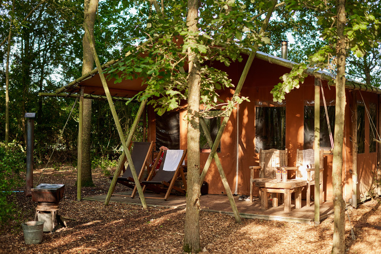 Safaritent met veranda, stoelen en privé warme douche bij Feather Down Layer Marney Tower, Verenigd Koninkrijk.