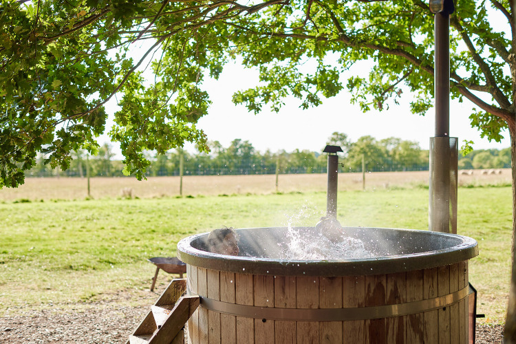 Ein Outdoor-Whirlpool neben einem Safarizelt mit privater Dusche bei Feather Down Layer Marney Tower.