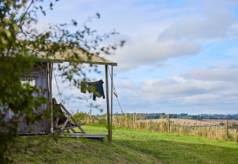 View across the English countryside from a safari tent with drying clothes at Billingsmoor Farm, UK.