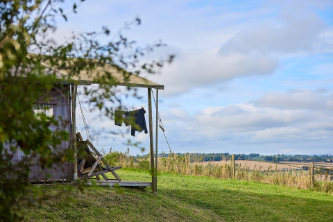 Vue sur la campagne anglaise depuis une tente safari avec du linge séchant à Billingsmoor Farm, Royaume-Uni.