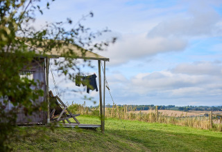 Vue sur la campagne anglaise depuis une tente safari avec du linge séchant à Billingsmoor Farm, Royaume-Uni.