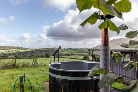 Blick auf grüne Hügel von einem Safari-Zelt mit privatem Hot-Tub auf Billingsmoor Farm, Großbritannien.