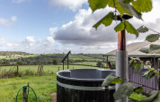 View over rolling countryside from a safari tent with private hot tub at Billingsmoor Farm, UK.