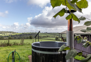Blick auf grüne Hügel von einem Safari-Zelt mit privatem Hot-Tub auf Billingsmoor Farm, Großbritannien.