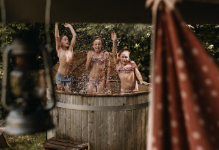 Niños juegan en una bañera caliente junto a una tienda safari con ducha privada en Het Wesselink, Salland.