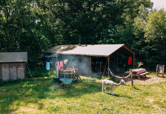 Casa de tienda safari con ducha privada caliente, bañera de hidromasaje y entorno natural exuberante.
