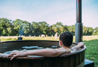 Persona relajándose en un jacuzzi exterior junto a la tienda safari en Feather Down Landgoed Volenbeek.