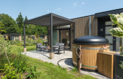 Buiten terras met zitjes en hottub bij Batenburgh Deluxe lodge, Veluwepark de Bosgraaf, Nederland.