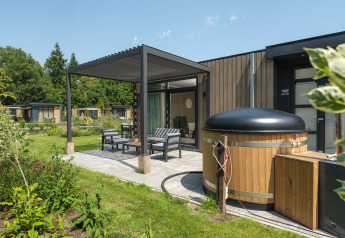 Udendørs terrasse med siddepladser og spabad ved Batenburgh Deluxe-lodge, Veluwepark de Bosgraaf, Holland.