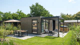 Moderne lodge bij Batenburgh Deluxe met terras, tuinmeubilair en groene tuin omgeven door beplanting.