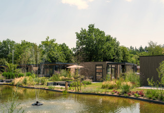 Batenburgh Deluxe lodge at Veluwepark de Bosgraaf, Netherlands, with pond, fountain and lush green surroundings.