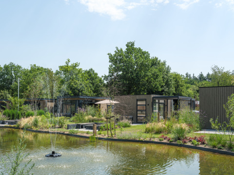 Luxuriöse Lodge Batenburgh Deluxe im Veluwepark de Bosgraaf, Niederlande, mit Teich, Springbrunnen und Natur.