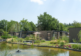 Lodge Batenburgh Deluxe al Veluwepark de Bosgraaf nei Paesi Bassi, con stagno, fontana e tanto verde.