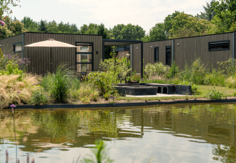 Batenburgh Deluxe lodge in Veluwepark de Bosgraaf, Nederland, moderne gevel, vijver en groene omgeving.