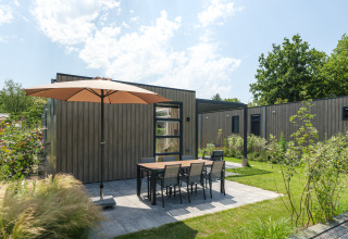 Terrazza esterna con ombrellone e tavolo presso il lodge Batenburgh Deluxe a Veluwepark de Bosgraaf, Paesi Bassi.