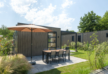 Außenterrasse mit Sonnenschirm und Sitzbereich bei der Batenburgh Deluxe Lodge im Veluwepark de Bosgraaf.