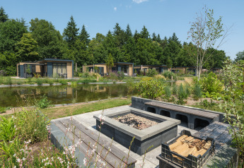 Lodges Batenburgh Deluxe en Veluwepark de Bosgraaf con modernas cabañas, estanque y áreas verdes en Países Bajos.