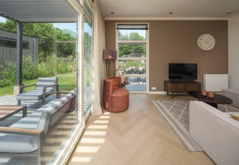 Modernes Wohnzimmer mit großen Fenstern in der Batenburgh Deluxe Lodge, Veluwepark de Bosgraaf, Niederlande