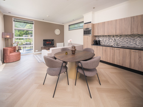 Soggiorno e cucina moderni al Batenburgh Deluxe lodge a Veluwepark de Bosgraaf, Paesi Bassi, con arredi eleganti.